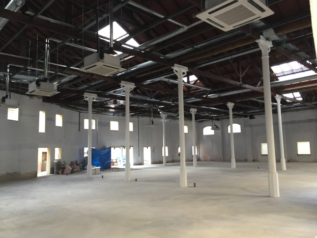 Large industrial warehouse space with numerous windows, structural pillars, overhead lighting, air conditioning units, and an open floor plan available for rent.